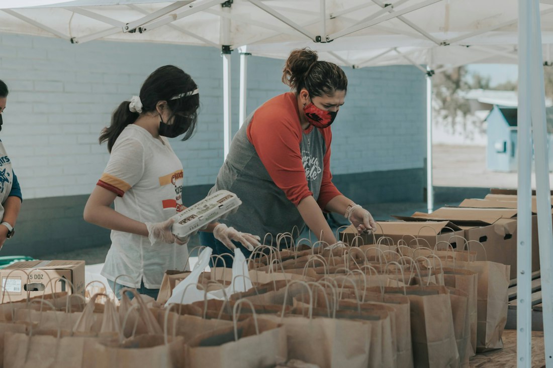 Volunteers packing paper grocery bags under a tent